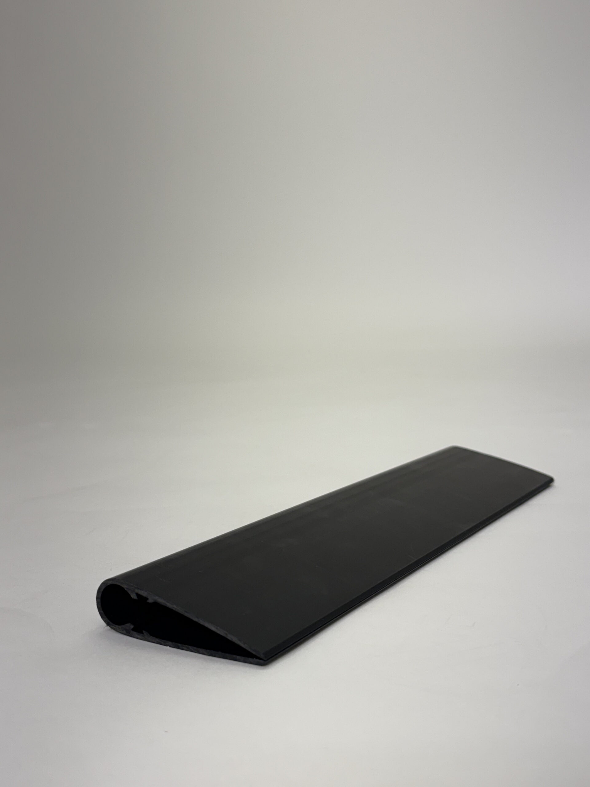 Long black rolled strip of material resting on a white surface.